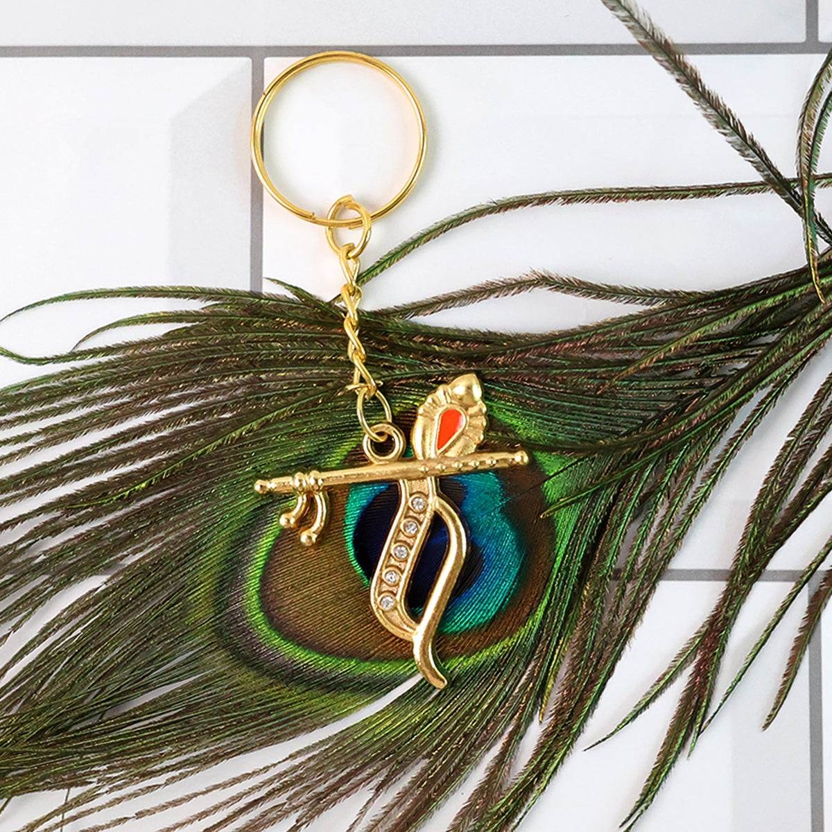 Side view of Krishna metal keychain highlighting flute and peacock feather motif