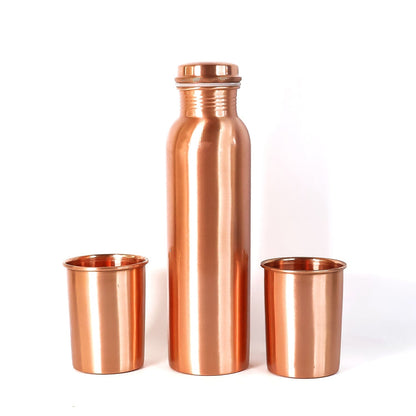 A person pouring water from the leakproof copper bottle into one of the matching glasses.