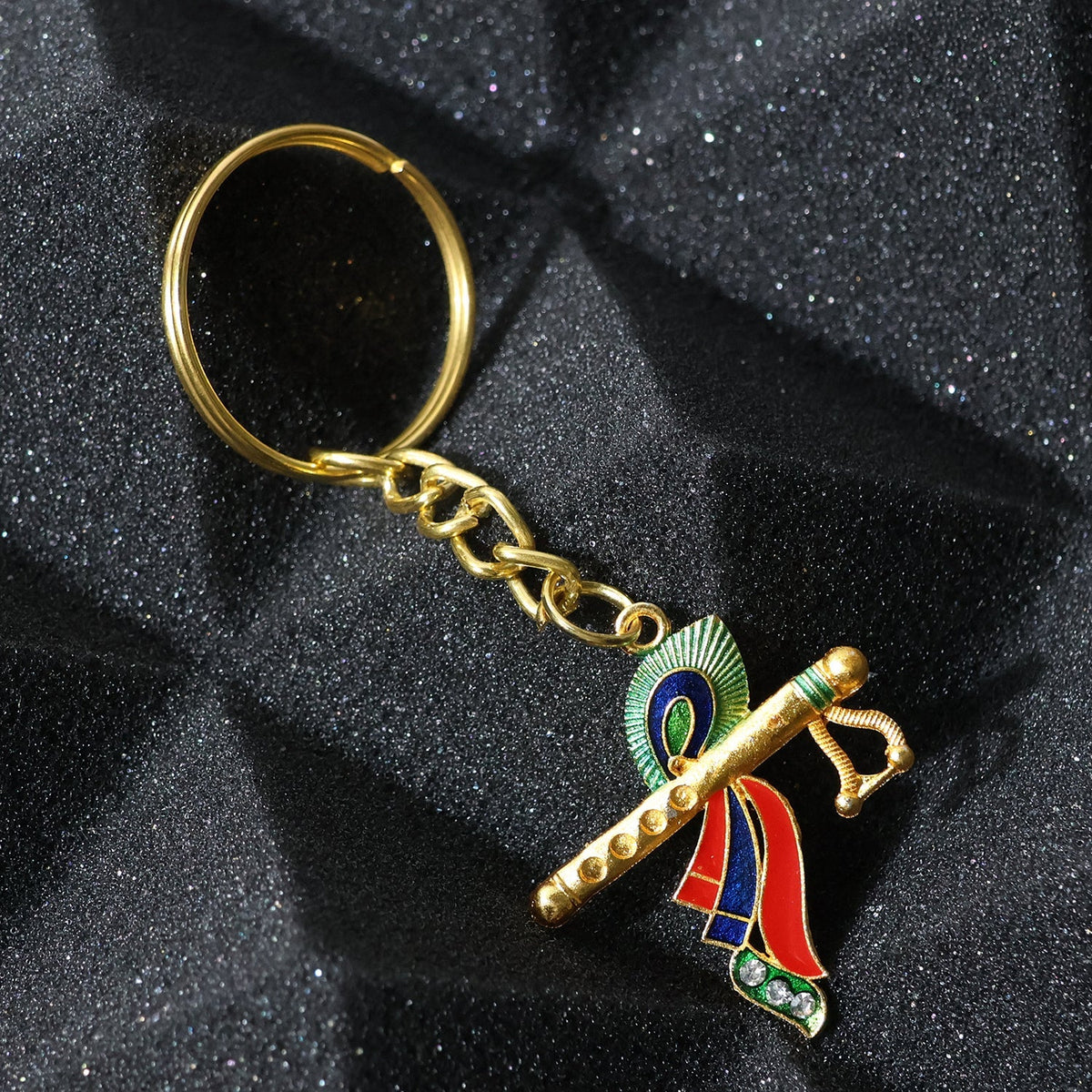 Close-up of Krishna metal keychain featuring flute and peacock feather motif